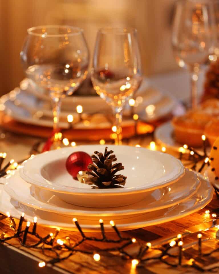 A softly lit Christmas table set with candles, greenery and simple elegant place settings, creating a warm and inviting holiday atmosphere.