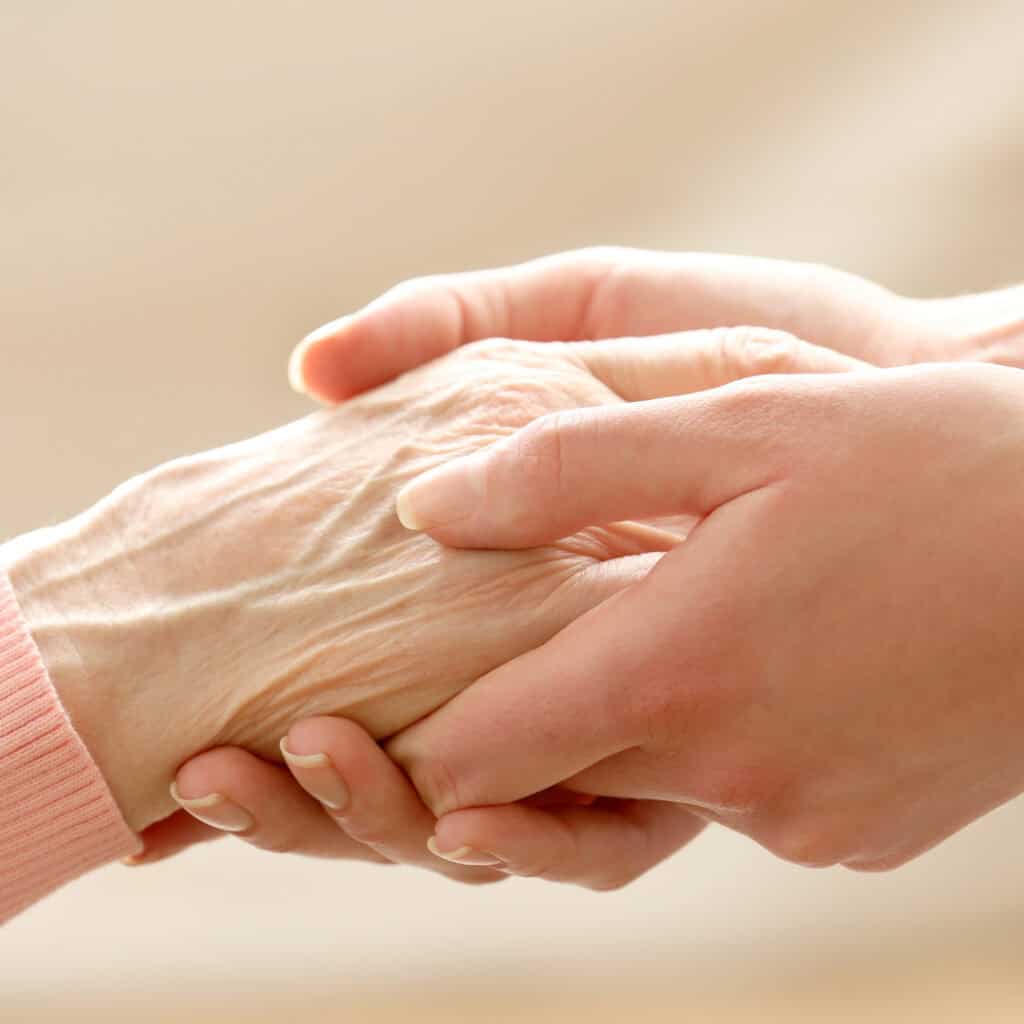 Young hand gently holding an elderly hand, symbolizing support, compassion, and advance care planning conversations.