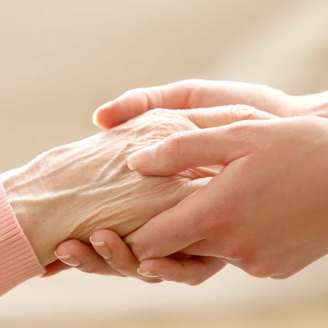 Young hand gently holding an elderly hand, symbolizing support, compassion, and advance care planning conversations.